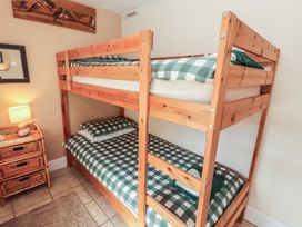 A bunk bed with checkered bed linen in a bedroom at Piggery Cottage in Wigton