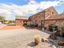 An outdoor area with a stone house and seating at Piggery Cottage in Wigton