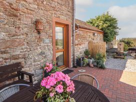 An outdoor area featuring a door, table, flowers, and a sign at Piggery Cottage in Wigton