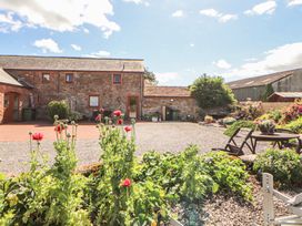 An outdoor area with a building and flowers at Piggery Cottage in Wigton
