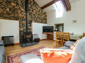 A living room with a wood stove, television, and dining table at Bythyn Ddol Hafod, Capel Curig