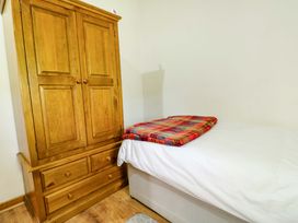 A bedroom with a wooden wardrobe and a bed at Bythyn Ddol Hafod in Capel Curig