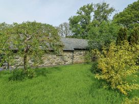 A garden with a stone wall and trees at Bythyn Ddol Hafod in Capel Curig
