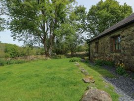 A garden with trees and a stone building at Bythyn Ddol Hafod Capel Curig