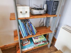 A shelf with books, board games, a radio, and a storage box at Lough Cluhir Cottage, Union Hall, County Cork
