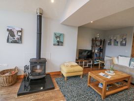 A living room with a wood stove and seating area at Lough Cluhir Cottage in Union Hall, County Cork