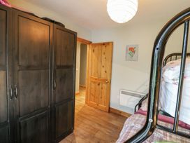 A bedroom with a wardrobe and a bed at Lough Cluhir Cottage in Union Hall, County Cork