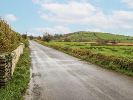 A countryside road with a hedge and hills at Lough Cluhir Cottage in Union Hall, County Cork