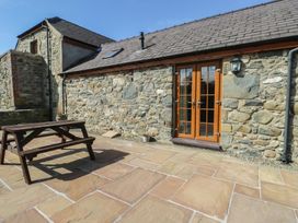 An outdoor area with a wooden table and stone walls at Lily Cottage in Caeathro near Caernarfon
