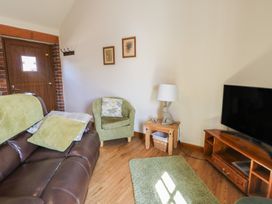 A living room with a sofa and television at Lily Cottage in Caeathro near Caernarfon