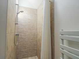 A shower area with tiled walls and a shower head at Lily Cottage in Caeathro near Caernarfon