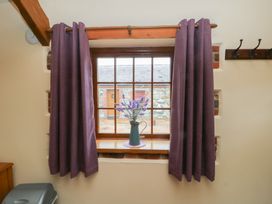 A window with curtains and flowers on the sill at Lavender Cottage in Caeathro near Caernarfon