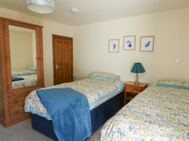 A bedroom with two beds and a mirror cabinet at Bluebell Cottage in Caeathro near Caernarfon