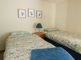 A bedroom with two beds and framed art on the wall at Bluebell Cottage in Caeathro near Caernarfon