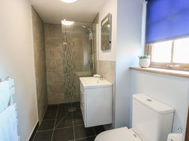 A bathroom with shower, vanity unit, and toilet at Bluebell Cottage in Caeathro near Caernarfon