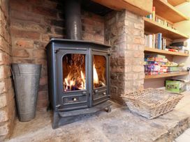 A wood stove with a fire in front of shelves and a basket at The Lodge Snainton near Scarborough