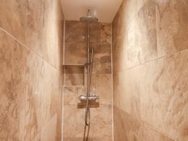A shower with a showerhead and wall tiles at The Lodge in Snainton near Scarborough