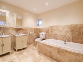 A bathroom with a bathtub, sink, toilet, and mirrors at The Lodge in Snainton near Scarborough