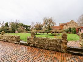A garden with picnic tables and a stone wall at The Lodge in Snainton near Scarborough
