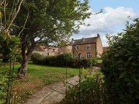 A garden with a house and pathway at The Lodge in Snainton near Scarborough
