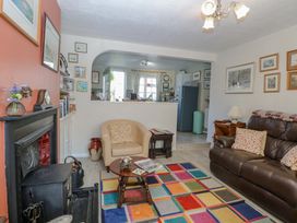 A living room with a leather sofa armchair colorful rug fireplace and a view into the kitchen at Peggottys Kelsale near Saxmundham