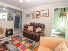 A living room with leather sofas colorful rug and kitchen area in the background at Peggotty's Kelsale near Saxmundham