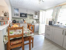 A kitchen with wooden chairs around a table and grey cabinets at Peggotty's in Kelsale near Saxmundham