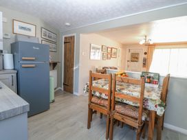 A kitchen dining area with a wooden table and chairs a blue refrigerator and framed pictures on the wall at Peggotty's in Kelsale near Saxmundham