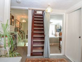 A stairway between a hallway with a plant and a bedroom with a bed and dresser at Peggotty's Kelsale near Saxmundham