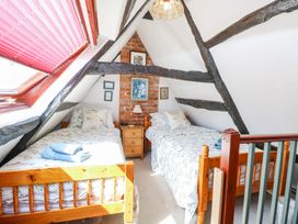 A bedroom with two single beds with floral bedding and wooden frames under a slanted ceiling with exposed beams at Peggotty's in Kelsale near Saxmundham
