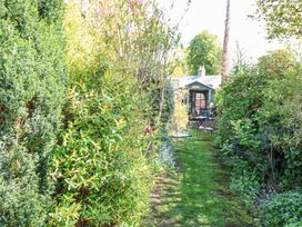 A garden path with green grass and chairs leading to a gazebo surrounded by bushes at Peggotty's Kelsale near Saxmundham