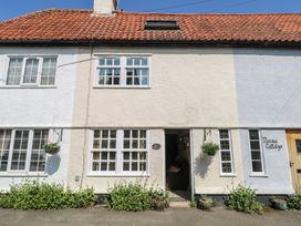 Exterior of a white terraced cottage with multiple windows flower pots and hanging baskets at Peggotty's in Kelsale near Saxmundham