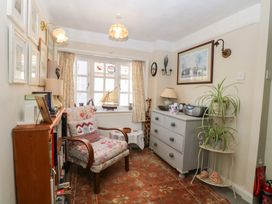 A small sitting room with armchair bookshelf dresser plants and a window at Peggotty's in Kelsale near Saxmundham
