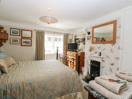 A bedroom with a double bed chest of drawers and a fireplace at Peggotty's in Kelsale near Saxmundham