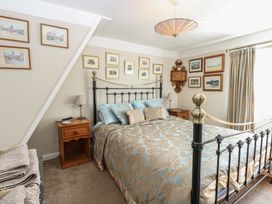 A bedroom with a metal bed frame beige and blue bedding two wooden bedside tables and framed pictures on the walls at Peggotty's in Kelsale near Saxmundham