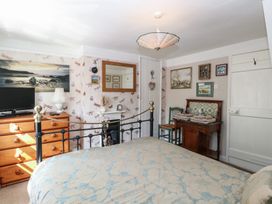 A bedroom with a bed dresser mirror and framed pictures at Peggotty's in Kelsale near Saxmundham