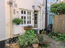 A small outdoor garden area with potted plants a hanging basket a round table and a green plastic chair at Peggottys in Kelsale near Saxmundham