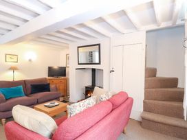 A living room with a sofa, armchair, and television at Broom Cottage in East Rudham near Fakenham