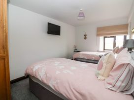 A bedroom with two beds and a television mounted on the wall at Wethercote Cottage Old Byland near Helmsley