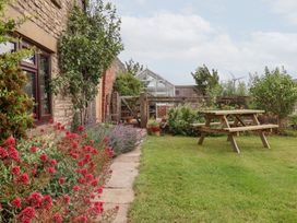 A garden with flowers, a pathway, and a table at Wethercote Cottage in Old Byland near Helmsley