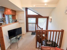 A living room with a tv and glass table at Wood Cottage in Kendal