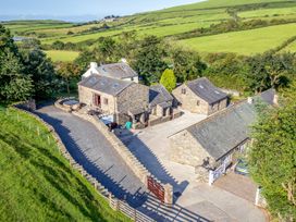 An outdoor view of a property with stone buildings and a parking area at Woodside Barn in Pennington near Ulverston