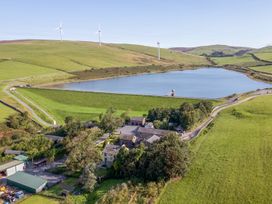 An aerial view of a farmhouse near a lake and wind turbines at Woodside Barn Pennington near Ulverston