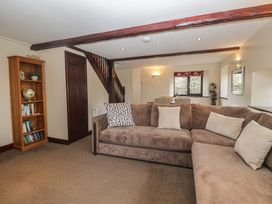 A living room with a sofa and bookshelf at Woodside Barn Pennington near Ulverston