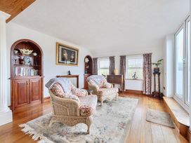 A living room with armchairs and a bookshelf at Chapel Green in Polgooth