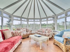 A conservatory with sofas and a coffee table at Chapel Green in Polgooth