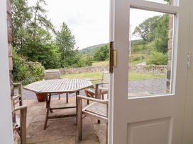 A patio with a wooden table and chairs at Bryn Howell Stables Trevor near Llangollen
