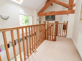 A landing with wooden railing and books on the shelf at Bryn Howell Stables Trevor near Llangollen