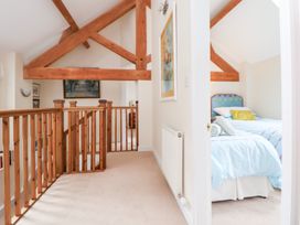 A landing with wooden railings and a view into a bedroom at Bryn Howell Stables in Trevor near Llangollen