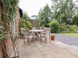 A patio with a wooden table and chairs at Bryn Howell Stables, Trevor near Llangollen